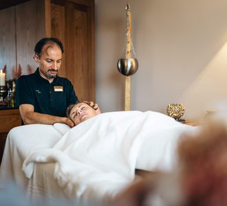 Eine Frau liegt auf einer Massageliege und bekommt eine Kopfmassage.