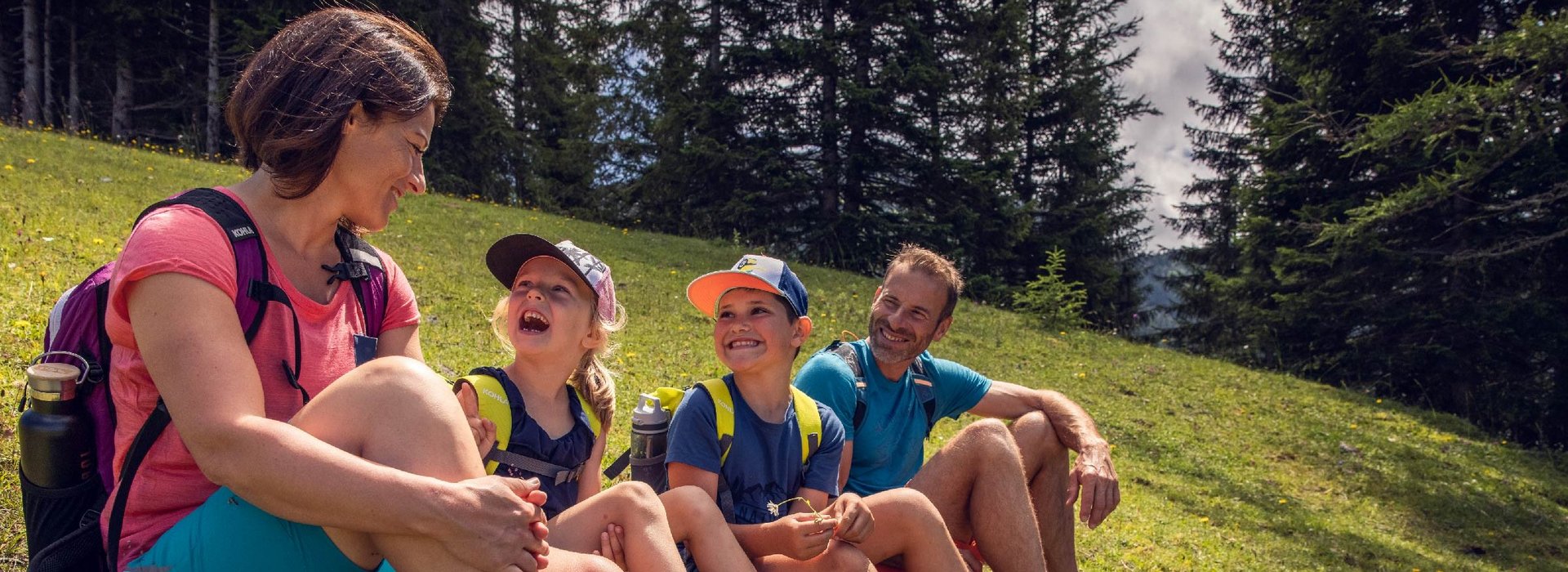 Eine Familie sitzt zusammen auf einer grünen Wiese.