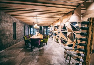 Ein moderner Weinkeller mit großem Esstisch und Weinregalen.