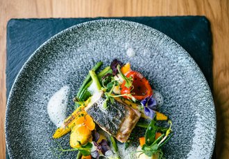 Ein Gericht mit Fisch und Gemüse auf einem Teller.