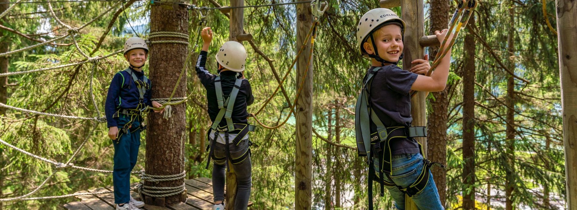 Drei Kinder klettern in einem Klettergarten.